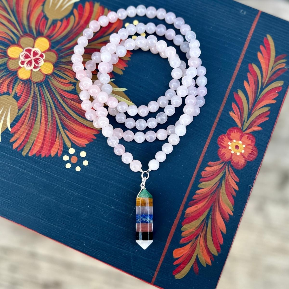 Chakra Balancing Necklace. Deeply meditative to wear, this Chakra Balancing Necklace brings the body’s seven main Chakras into alignment. Rose quartz is an excellent heart-healing gemstone. The colorful gemstones on the centerpiece correspond to the seven different chakras.