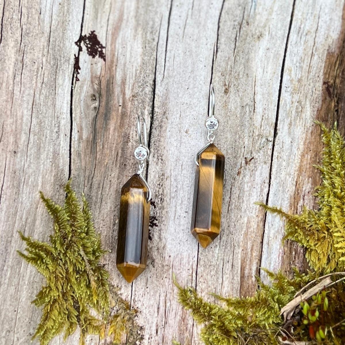 The Empowerment Enhancer Earrings made of Tiger Eye are a striking pair of earrings that embody the strength and confidence of the majestic tiger. Each earring features a polished Tiger Eye stone, which is known for its unique golden-brown color and distinctive chatoyancy, or "cat's eye" effect.