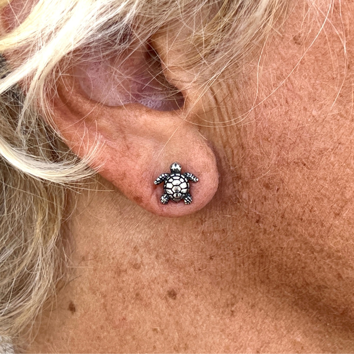 These sterling silver turtle earrings are a charming addition to any jewelry collection. The earrings feature a pair of baby sea turtles, crafted in intricate detail with their shells, flippers, and heads. The earrings are designed as post earrings, making them easy and comfortable to wear.